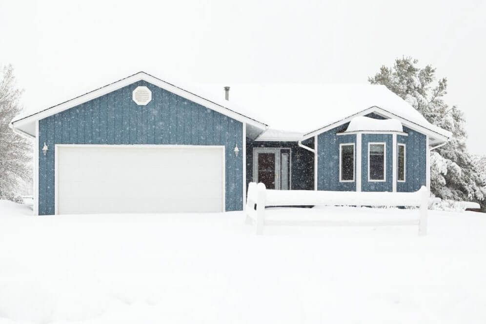 White garage door on blue exterior home in the winter