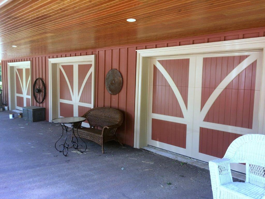 Red Wood Swing Style Carriage Garage Door With White Accents On A Red Barn