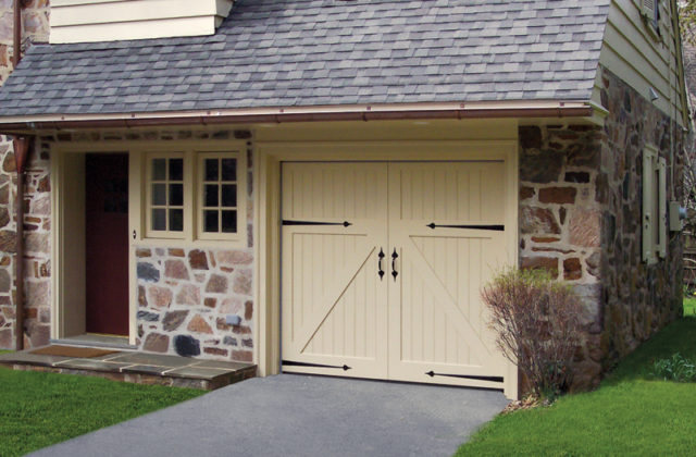 Bifold white wood garage door with v-buck trim and black decorative hardware