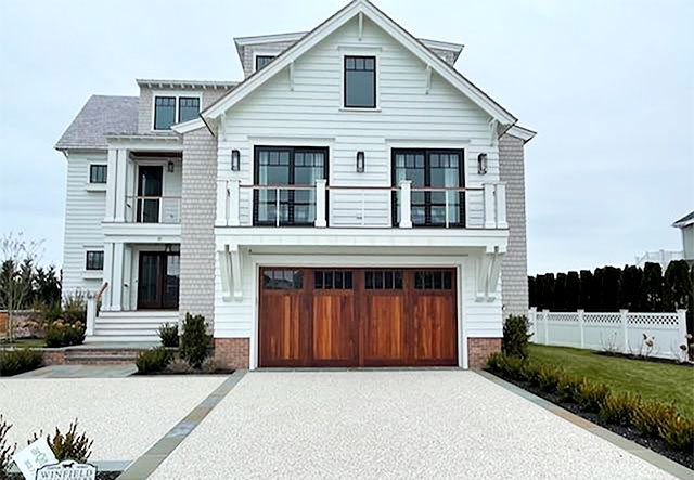 White villa style house with mahogany wood garage door with a brown stain and windows