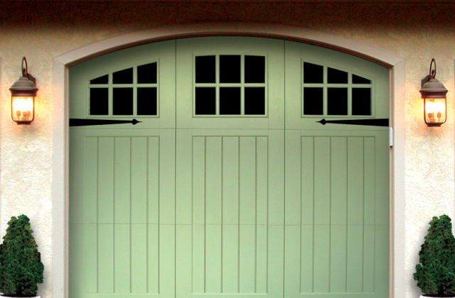 Light mint green vinyl garage door with windows and decorative hardware on a gray garage