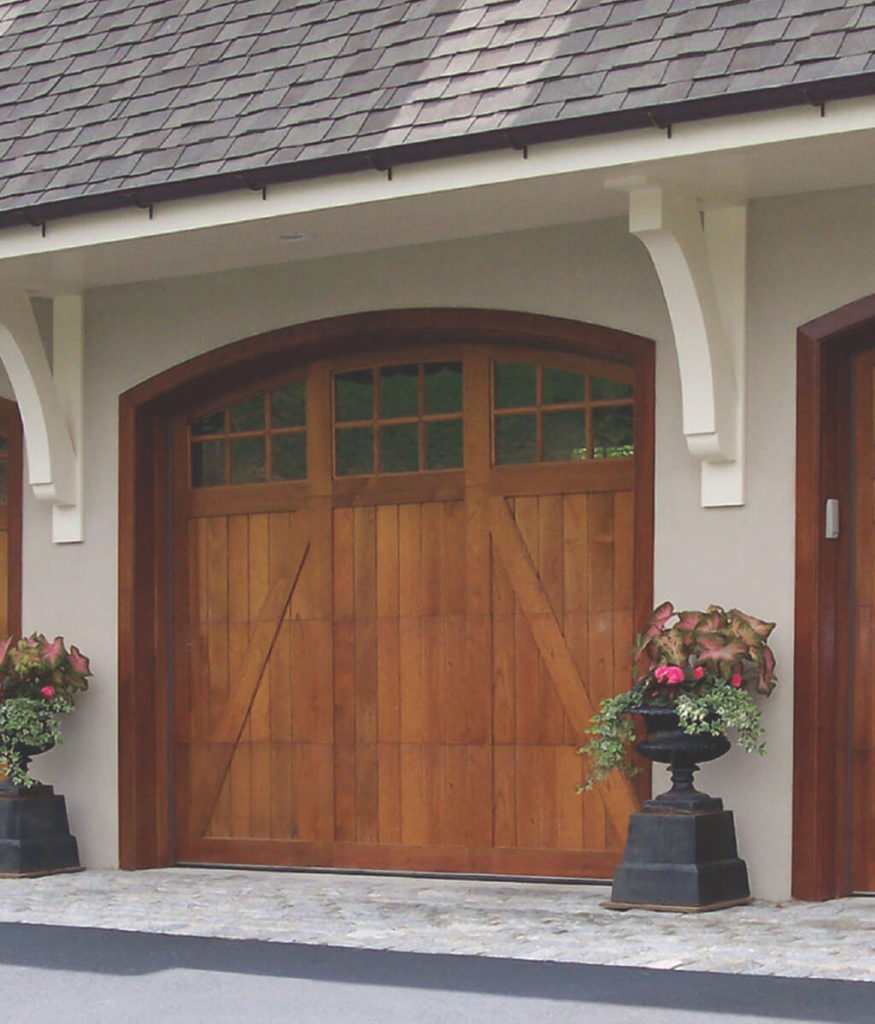 Arched wooden garage door with three windows on a white garage