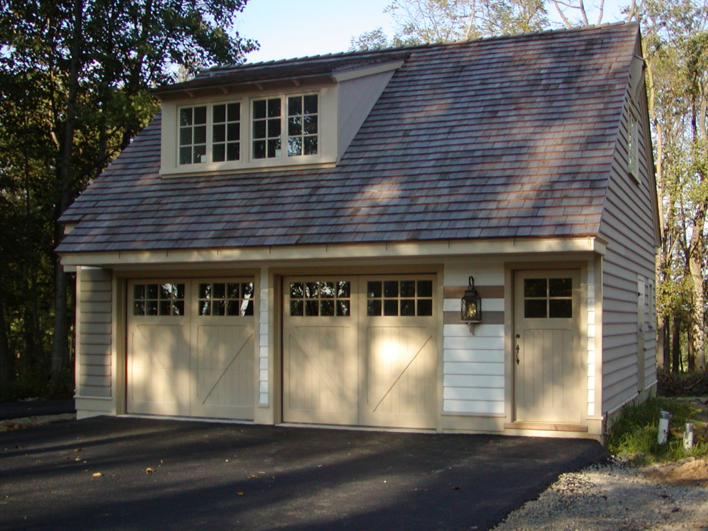 Custom beige painted true swing carriage garage door on a detached garage