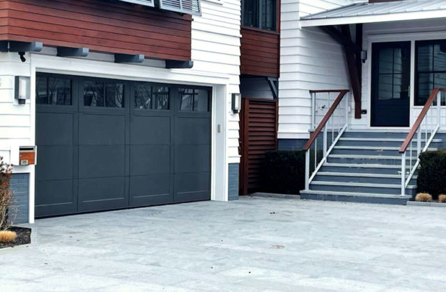 Dark gray stained accoya wood garage door with windows on a modern beach house