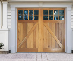 Light natural brown wooden garage door with z buck panels, two rectangular windows on vinyl garage