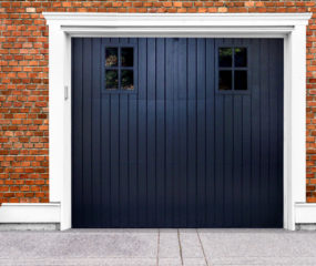 Black wooden garage door with two rectangular windows on brick garage
