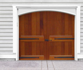 Brown arched swing out wooden garage door with no windows, door straps on white vinyl garage