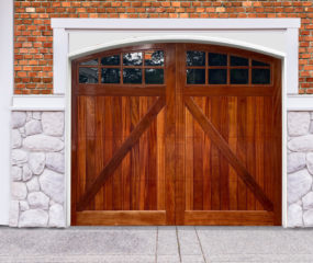 Brown arched swing out garage door with v bucks and two windows on brick and stone garage