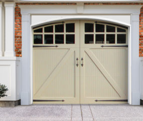 Light beige swing out wooden garage door with windows, door straps, and handles