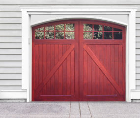 Red stained arched swing out wooden carriage garage door with two windows and z buck panels