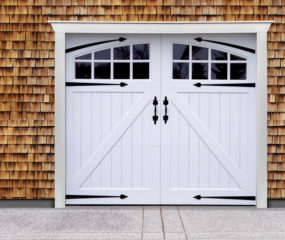 White vinyl carriage garage door with z buck panels, two windows, door straps, and door handles
