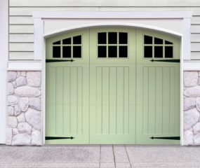 Green vinyl carriage house garage door with three panels and windows with door straps