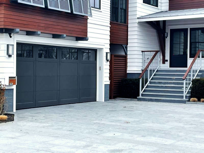 A navy blue garage door installed on a white house. 