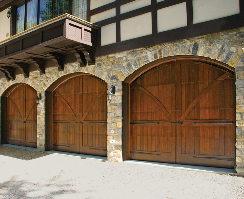 Three wooden garage doors that mimic the historic carriage door style. 
