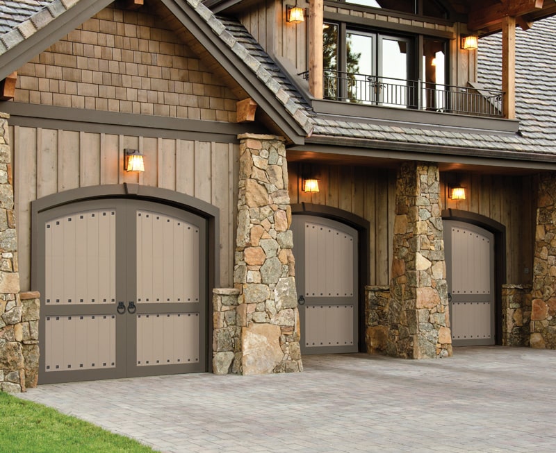 three brown and tan carriage garage doors with clavos and ring pulls as decorative hardware.