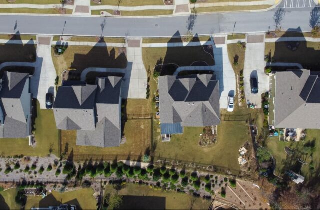 overview of four roofs with driveways and fence yards.