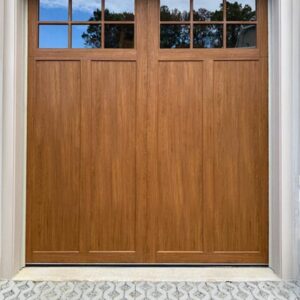 composite wood garage door with a warm wood finish and top window inserts.