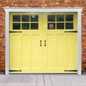 Yellow wood composite garage door with square windows, strap hinges, and door handles on brick garage