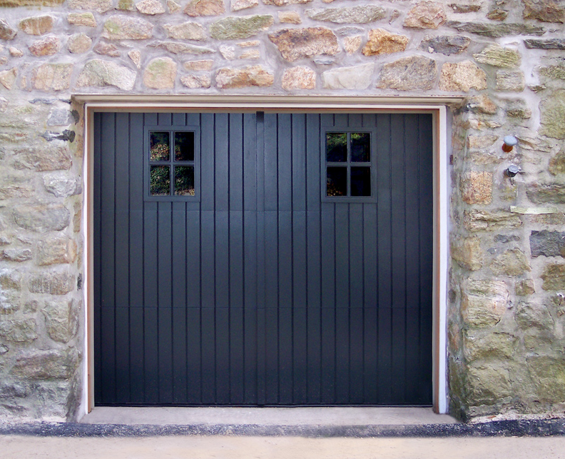 Black barn styled garage door with garage door windows on a stone garage