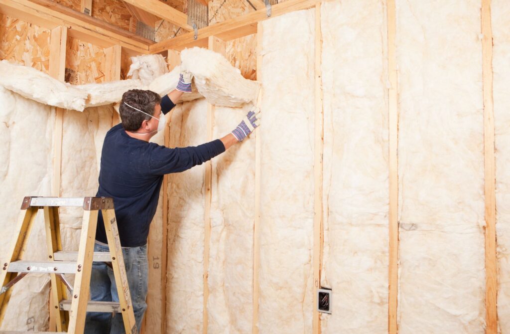 Man adding insulation to garage walls to increase garage energy efficiency