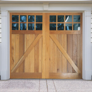 Light natural brown wooden garage door with z buck panels, two rectangular windows on vinyl garage