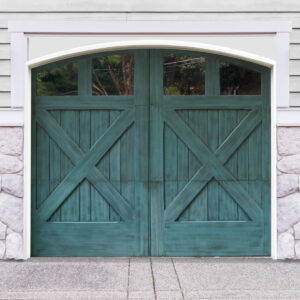 Teal arched swing out garage door with four windows and cross bucks on white vinyl and stone garage