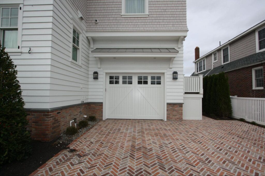 a white garage door with four sets of windows and two exterior lights on either side of the garage door.
